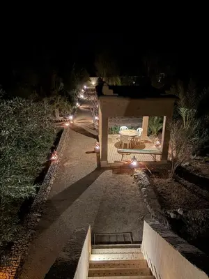 a pathway with a table and lights at night at Skoura Ranch Palm Grove in Ouarzazate