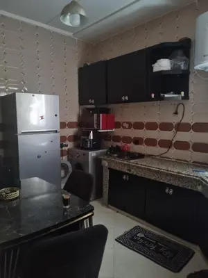 a kitchen with black cabinets and a white refrigerator at Vip apartment in Fès