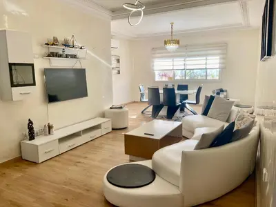a living room with white furniture and a television at You'll be comfortable there! in Fès