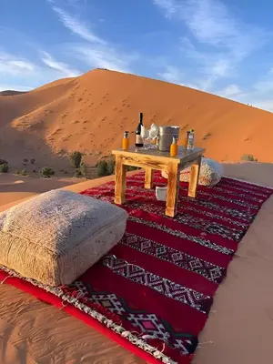 a table on a rug in the desert at Starry Luxury Camp in Merzouga