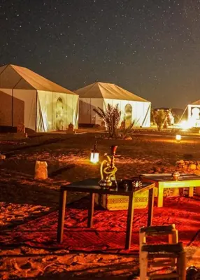 a group of tents in the desert at night at Starry Luxury Camp in Merzouga