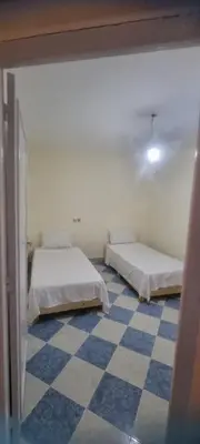 two beds in a room with a checkered floor at Gite El Qalaa - مأوى القلعة in Taza