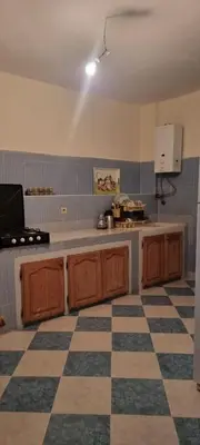 a kitchen with wooden cabinets and a checkered floor at Gite El Qalaa - مأوى القلعة in Taza