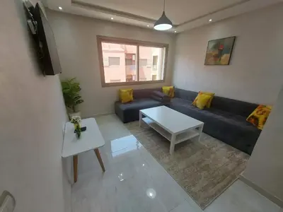 a living room with a blue couch and a table at Appartement centre ville in Oulad Akkou