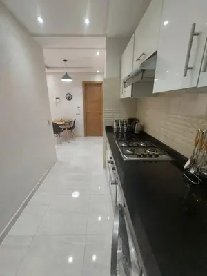 a kitchen with a black counter top and a table at Appartement centre ville in Oulad Akkou