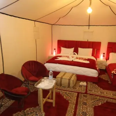 a bedroom with a bed and chairs in a tent at Merzouga tente luxury in Merzouga