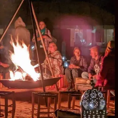 a group of people sitting around a fire at Merzouga tente luxury in Merzouga