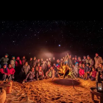 a group of people sitting around a fire at Merzouga tente luxury in Merzouga
