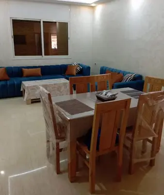 a dining room with a table and chairs and a couch at Quiet and central apartment in Oulad Akkou