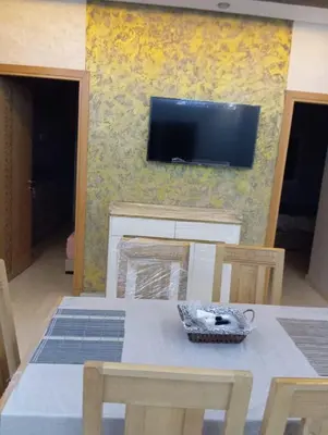 a dining room with a table and a tv on a wall at Quiet and central apartment in Oulad Akkou