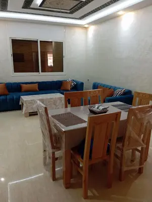 a living room with a table and chairs and a couch at Quiet and central apartment in Oulad Akkou