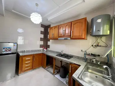 a small kitchen with wooden cabinets and a sink at Prestige Apartment - Fes Elegant Stay in Fès