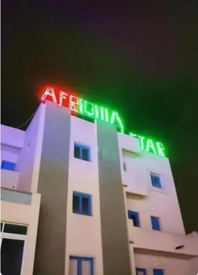 a white building with a neon sign on top of it at Afriquia Star in Oulad Akkou