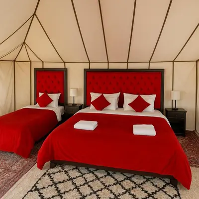 a bedroom with two red beds in a tent at Merzouga Stars Camp in Merzouga