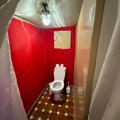 a small bathroom with a toilet in a red room at Merzouga Stars Camp in Merzouga
