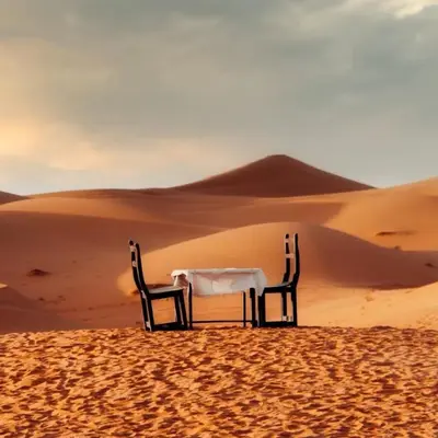 a table and two chairs in the desert at Merzouga Stars Camp in Merzouga