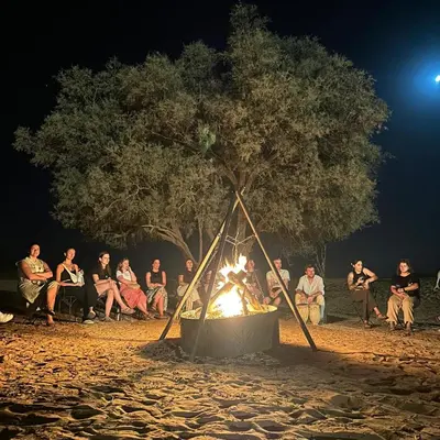 a group of people sitting around a fire at Merzouga Stars Camp in Merzouga