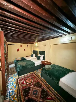 a hotel room with two beds and a rug at Riad Sufi House Fes in Fès