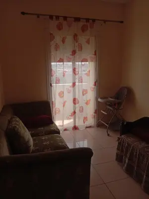 a living room with a couch and a window with a curtain at إقامة النور الصخيرات in Oulad Akkou