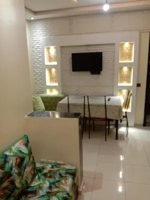 a living room with a table and a tv on a wall at إقامة النور الصخيرات in Oulad Akkou