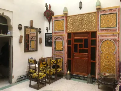 a room with a table and chairs and a wooden door at Reggae Riad in Fès