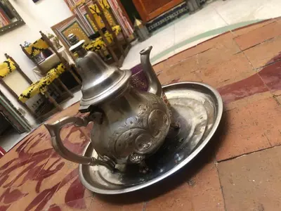 a metal tea pot sitting on a plate on the ground at Reggae Riad in Fès