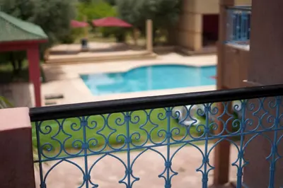 a balcony with a fence and a swimming pool at Villa H in Oulad Snaguia