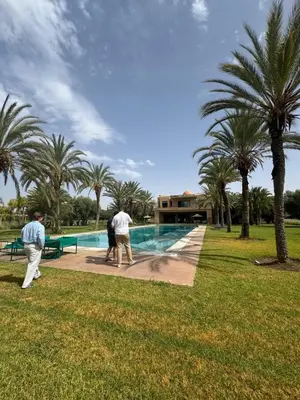 a group of people standing around a swimming pool at Villa H in Oulad Snaguia
