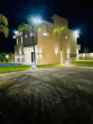 a building with palm trees in front of it at night at Villa Itran Marrakech in Aguelmous