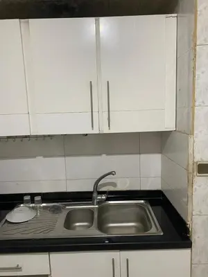 a kitchen counter with a sink and white cabinets at Azrou in Azrou