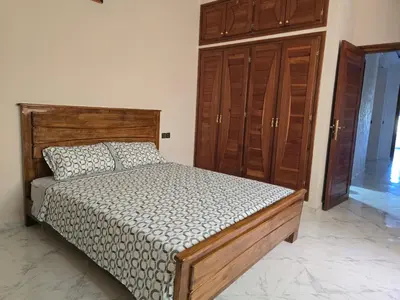 a bedroom with a bed and some wooden cabinets at belle vue à petit prix in Meknès