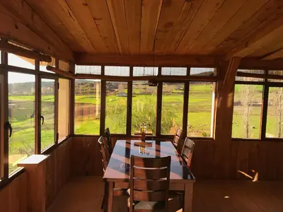 a dining room with a table and chairs and windows at Rise In Valley in Ifrane