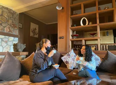two women sitting on a couch talking on their cell phones at Rise In Valley in Ifrane
