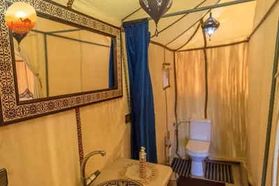 a bathroom with a mirror and a toilet in a room at Fatima Luxury desert camp in Merzouga