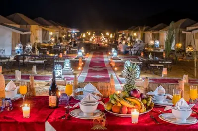 a table with plates of fruit and candles on it at Fatima Luxury desert camp in Merzouga