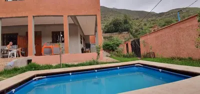 a blue swimming pool in front of a house at Villa d'Exception à Ourika Nichée au Cœur des Montagnes in Aghbalou