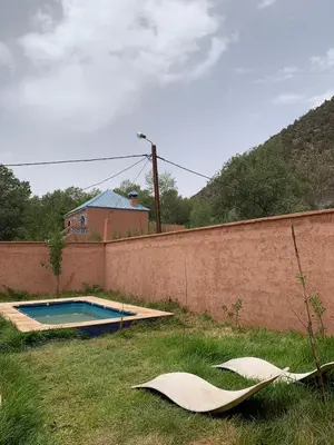 a swimming pool in the grass next to a wall at Villa d'Exception à Ourika Nichée au Cœur des Montagnes in Aghbalou