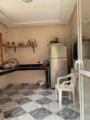 a kitchen with a refrigerator and a chair in it at Villa d'Exception à Ourika Nichée au Cœur des Montagnes in Aghbalou