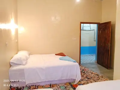 a bedroom with two beds and a door to a bathroom at Gîte Palma Eagle Ziz Canyon in Er Rachidia