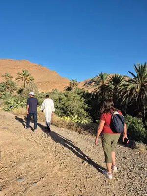 three people walking down a dirt road in the desert at Gîte Palma Eagle Ziz Canyon in Er Rachidia