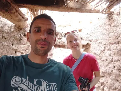 a man and a woman standing next to a stone wall at Gîte Palma Eagle Ziz Canyon in Er Rachidia