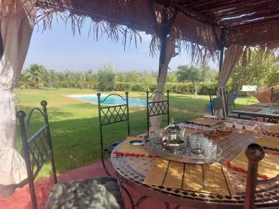 a table and chairs under a gazebo at Villa sur ferme, piscine & vue sur Atlas in Douar Tounsi