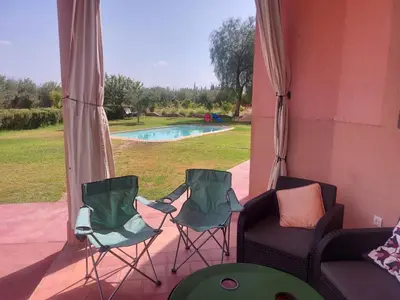 a porch with two chairs and a couch and a pool at Villa sur ferme, piscine & vue sur Atlas in Douar Tounsi