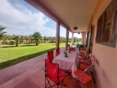 a patio with a table and chairs on a porch at Villa sur ferme, piscine & vue sur Atlas in Douar Tounsi