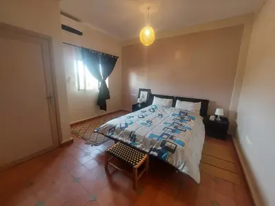 a bedroom with a large bed and a window at Villa sur ferme, piscine & vue sur Atlas in Douar Tounsi