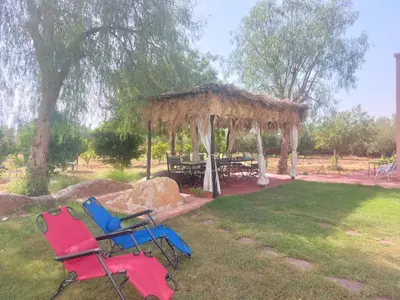 a group of chairs and a gazebo in a yard at Villa sur ferme, piscine & vue sur Atlas in Douar Tounsi