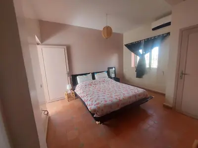 a bedroom with a bed in a room with a window at Villa sur ferme, piscine & vue sur Atlas in Douar Tounsi