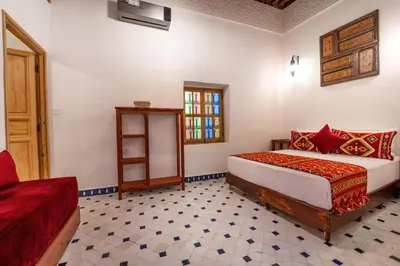 a bedroom with a bed and a window and a table at Riad Dar Sira in Fès