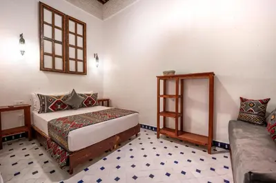 a bedroom with a bed and a window and a couch at Riad Dar Sira in Fès
