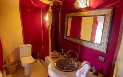 a bathroom with a sink and a toilet and a mirror at Luxury Sahara Gold Camp in Merzouga